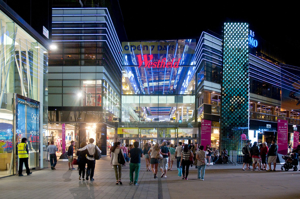 The outside of the a shopping centre lit up by LED lights and a neon red commercial sign