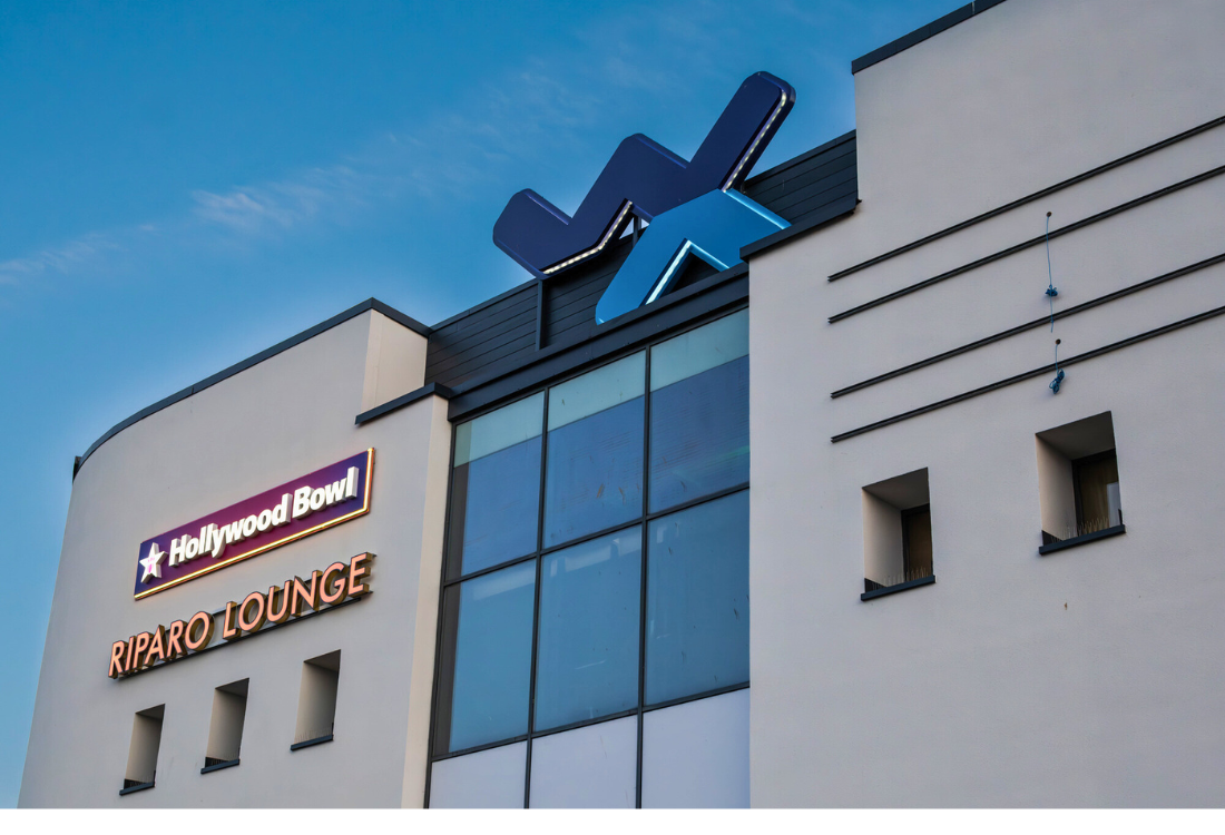 Modern business building with illuminated signage for Hollywood Bowl and Riparo Lounge, showcasing the importance of visibility and branding in sign design.