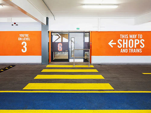 A wayfinding design with a memorable brand orange colour on the walls chosen through using logo signage design consultants