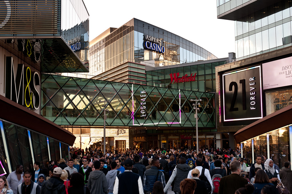 A crowd of customers going into a busy shopping centre due to the successful use of signage which has increased sales for the multiple businesses.