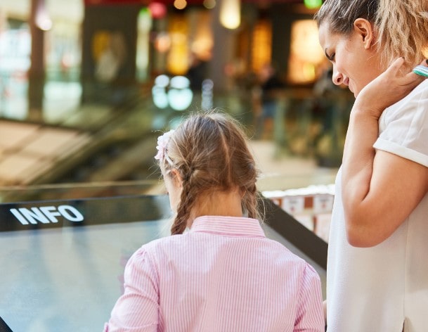 A mother and daughter using an information kiosk with an interactive screen for optimised wayfinding in a shopping centre