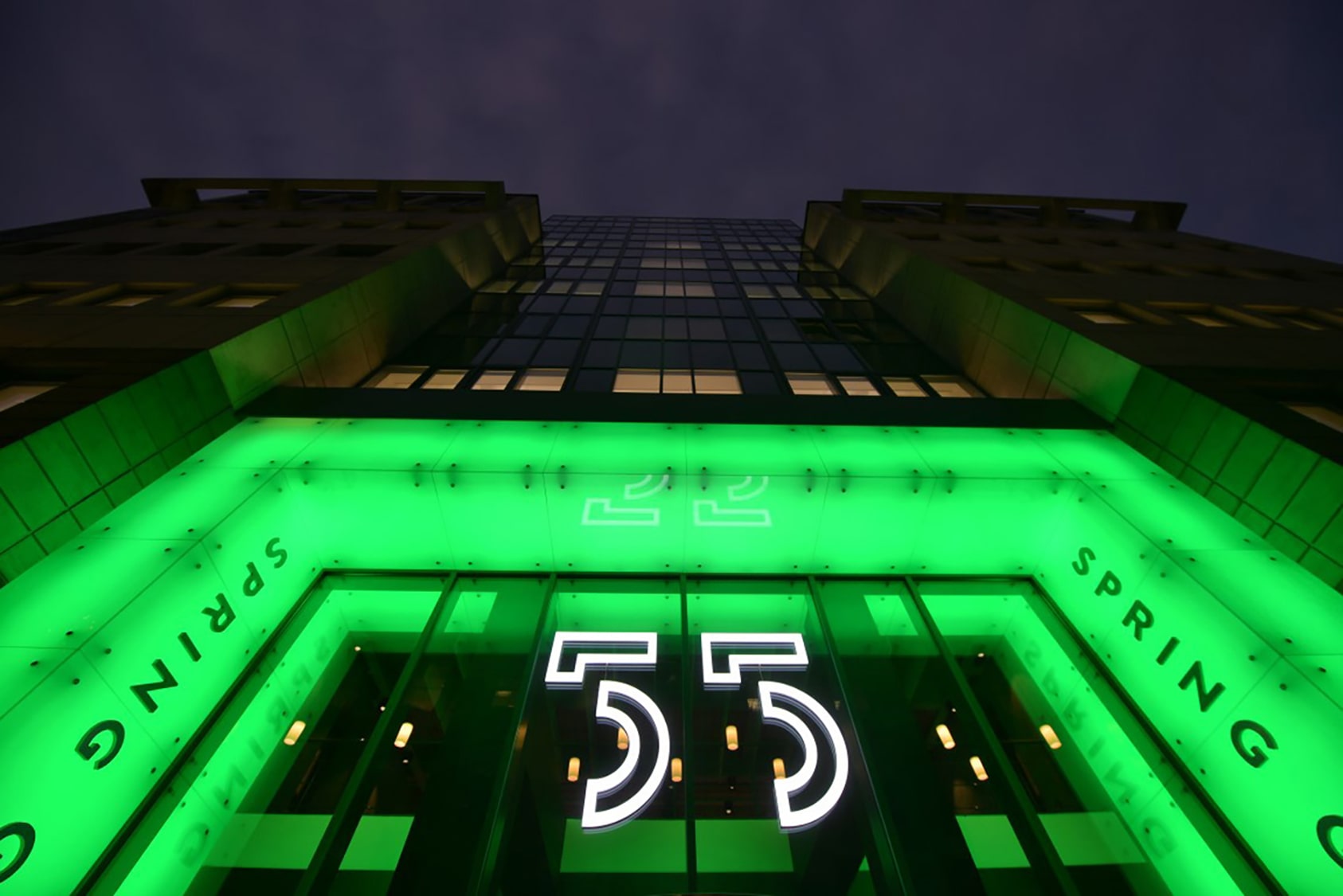 A neon green sign on the outside of a 55 building designed bespoke by Image Technique Sign Solutions